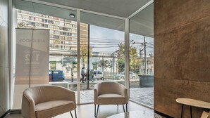A modern interior with two armchairs, a round table, and a glass door leading to a street view. - Modern 1Bedroom,1 bathroom,Terrace,Wash/Dry and WiFi 8min MetroL5 Santiago (Santiago)
