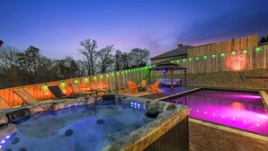 A hot tub with LED lights, a wooden deck, and outdoor seating. - Heated Pool Backyard Oasis | Pickleball-Basketball (Sevierville)
