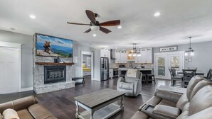 A spacious living room with a fireplace, leather sofas, a dining area, and a kitchen.