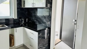 A modern kitchen with black marble countertops, white cabinets, and a black door. - Luxury & Grandeur Hawthorn Apt| Prime Location, Parking ! (Hawthorn)
