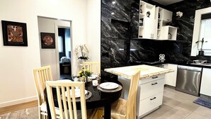 A modern kitchen with a black marble backsplash, white cabinets, and a built-in dishwasher. - Luxury & Grandeur Hawthorn Apt| Prime Location, Parking ! (Hawthorn)