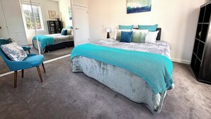 A bedroom with a large bed, a chair, a mirror, and a painting on the wall. - Luxury & Grandeur Hawthorn Apt| Prime Location, Parking ! (Hawthorn)