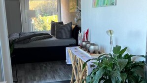 Ein modernes Wohnzimmer mit einer Couch, einem Esstisch mit Stühlen und einer großen Topfpflanze.