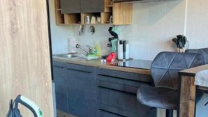 Eine moderne Küche mit Holzschränken, einer schwarzen Arbeitsplatte und einem grauen Sofa.