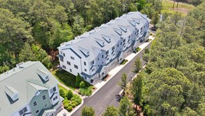 Um edifício residencial de vários andares, com design simétrico, rodeado por uma floresta densa.