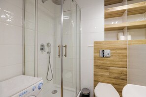 A modern bathroom with a glass-enclosed shower, a toilet, and a sink.
