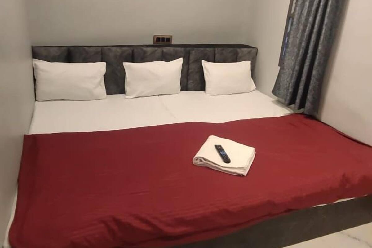 A bed with a red bedspread, white pillows, and a remote control on it.