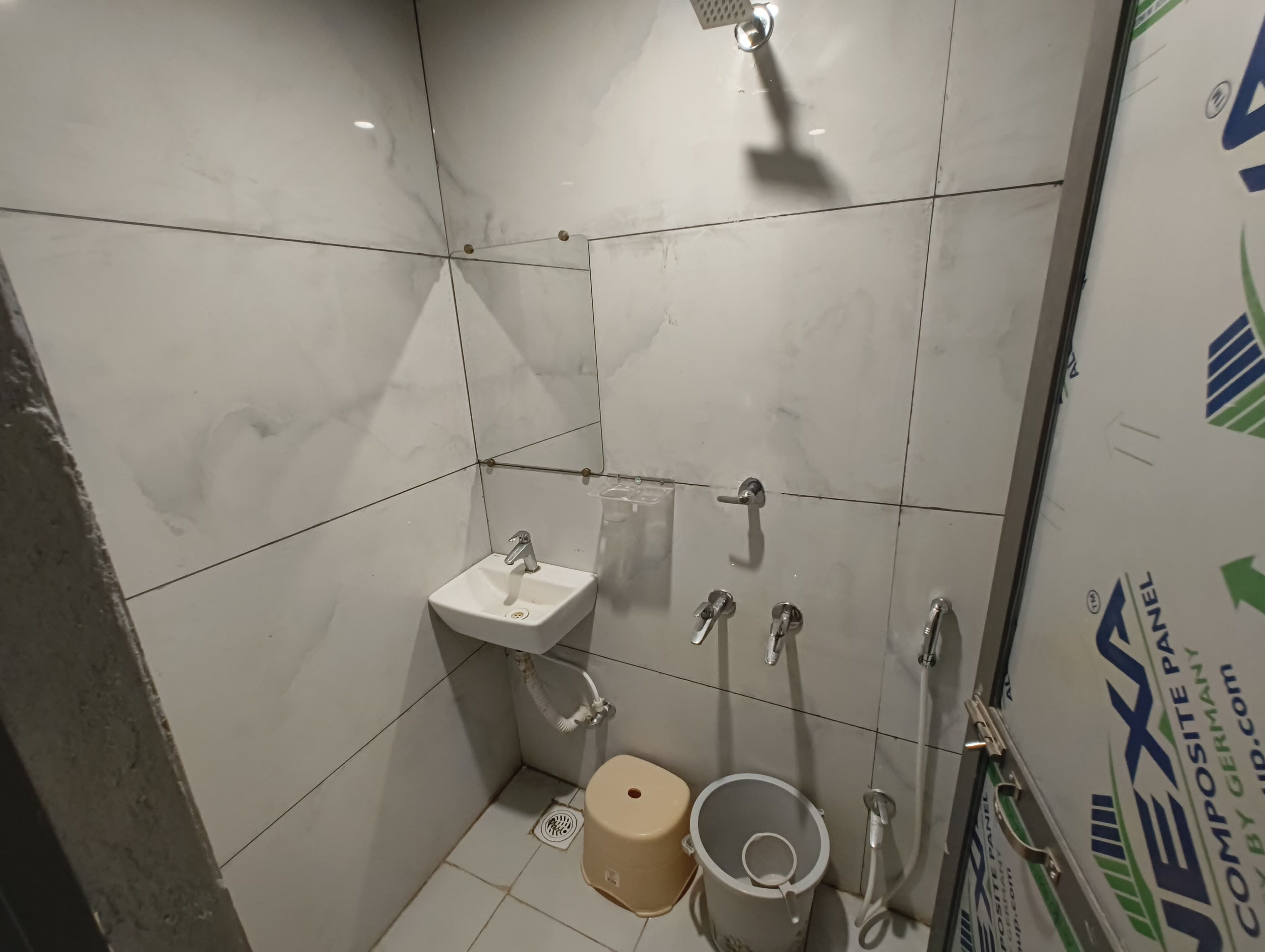Un baño pequeño con azulejos, que incluye un lavamanos, inodoro, ducha y secador de manos.