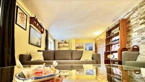 Un salon avec un canapé, une table basse en verre et un mur en pierre.