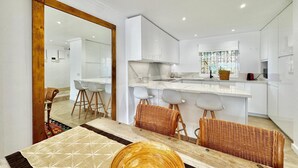 A modern kitchen with white cabinets, a marble countertop, and a large island with bar stools.