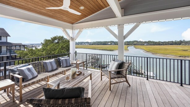 A covered deck with outdoor furniture, a ceiling fan, and a view of a river and landscape.