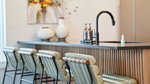 A modern kitchen with a bar area, bar stools, a sink, and decorative vases.