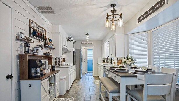 A kitchen with white cabinets, a coffee bar, and a dining area with a table set for two.