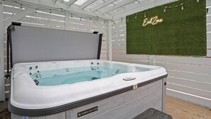 A hot tub in a covered outdoor area with a green wall and a neon sign that reads "End Zone."