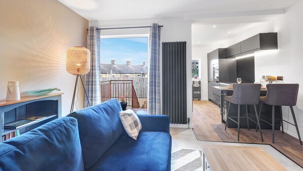 Un salon moderne avec un canapé bleu, un lampadaire et une vue sur la ville grâce à de grandes fenêtres.
