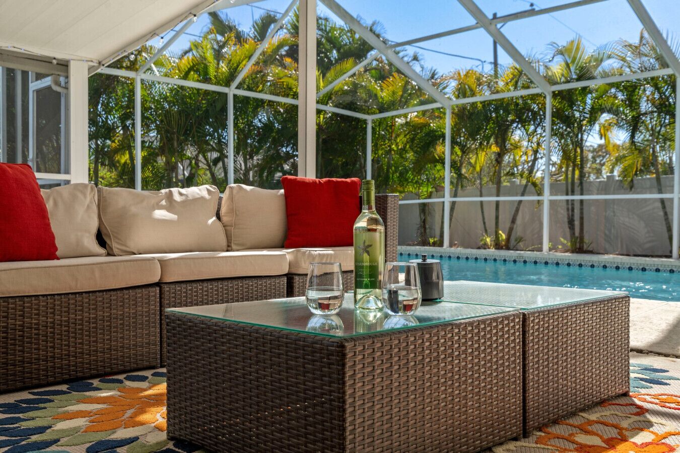 Uma área de estar coberta ao ar livre com piscina ao fundo.