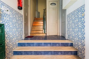 Stairs lead to an upper floor, flanked by patterned tiles and a handrail.