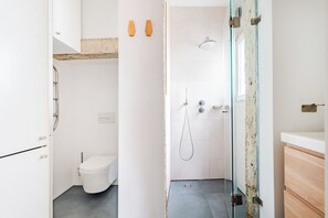 Ein modernes Badezimmer mit einer Glasdusche, einer weißen Toilette und einem Holzlagerflächen.
