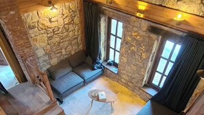 Ein gemütlicher Raum mit Steinwänden, einer Holztreppe, einer Sofagarnitur und einem kleinen Tisch.