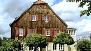 A large wooden building with multiple windows and a sloped roof. - Idyllic house with lots of extras in a beautiful natural setting (Sulzbach-Laufen)