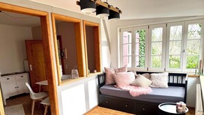 A cozy room with a wooden floor, a bed with pillows, a small table with candles, and a window with greenery outside. - Idyllic house with lots of extras in a beautiful natural setting (Sulzbach-Laufen)