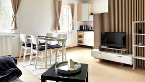 A modern living room with a dining area, a flat-screen TV, and a kitchen with a microwave. - Idyllic house with lots of extras in a beautiful natural setting (Sulzbach-Laufen)