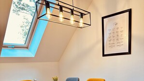 A dining area with a wooden table, four chairs, a modern pendant light, and a skylight. - Cosy two store apartment with the garage (Karpacz)