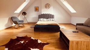 A bedroom with a sloped ceiling, a bed, a rocking chair, a sofa, a coffee table, and a cowhide rug. - Cosy two store apartment with the garage (Karpacz)
