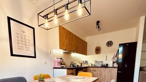 A modern kitchen with wooden cabinets, a black refrigerator, and a dining area with a wooden table and yellow chairs. - Cosy two store apartment with the garage (Karpacz)