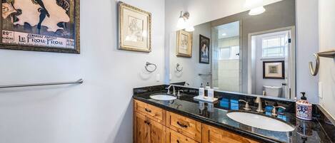 A bathroom with two sinks, wooden cabinets, and framed artwork on the walls.