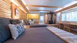 Een knus houten blokhutinterieur met een bed, een eettafel en een keukenhoek.