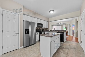 A modern kitchen with white cabinetry, stainless steel appliances, and a granite countertop.