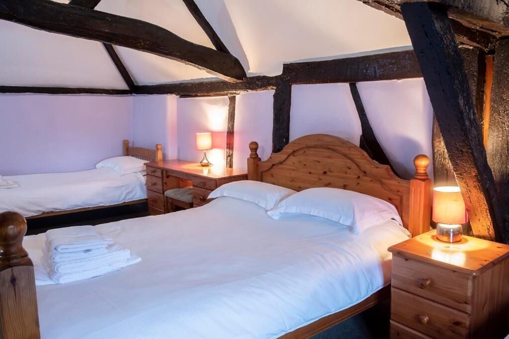 A cozy room with two beds, wooden headboards, and a nightstand with a lamp.