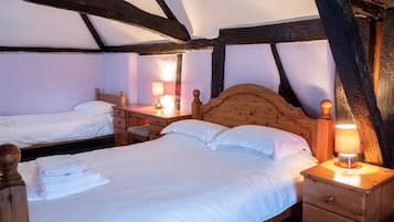 A cozy room with two beds, wooden headboards, and a nightstand with a lamp.