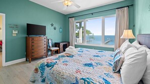 Una camera da letto con un letto, una cassettiera, una scrivania, una televisione e una finestra vista mare.