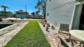 A residential property with a well-maintained lawn, outdoor seating area, and a house with a sliding glass door.