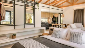 Une chambre à coucher moderne avec un lit, un canapé blanc et un coin repas à l’arrière-plan.