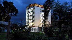 A multi-story hotel with balconies, a fenced garden area, and a night-time setting. - Clayton Luxury Suite (Machakos)