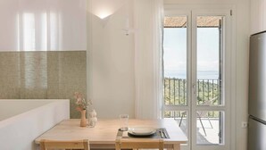 Een moderne keuken met een houten tafel gedekt voor twee personen, een koelkast en uitzicht op het groen door een glazen deur.