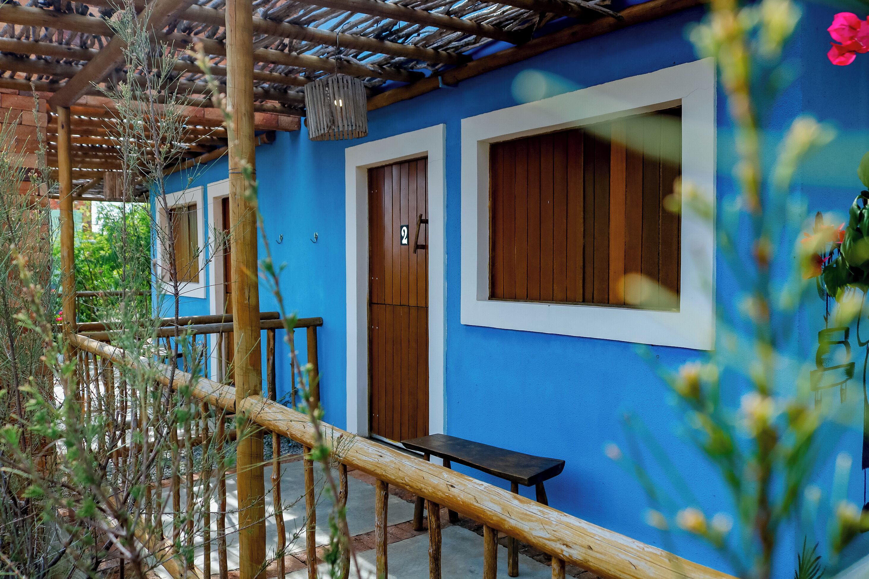 A blue building with wooden doors and windows, a wooden bench, and a bamboo fence.