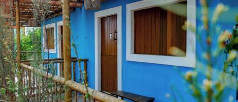 A blue building with wooden doors and windows, a wooden bench, and a bamboo fence.