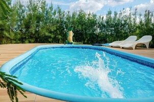 Una piscina con cubierta de madera, rodeada de árboles.