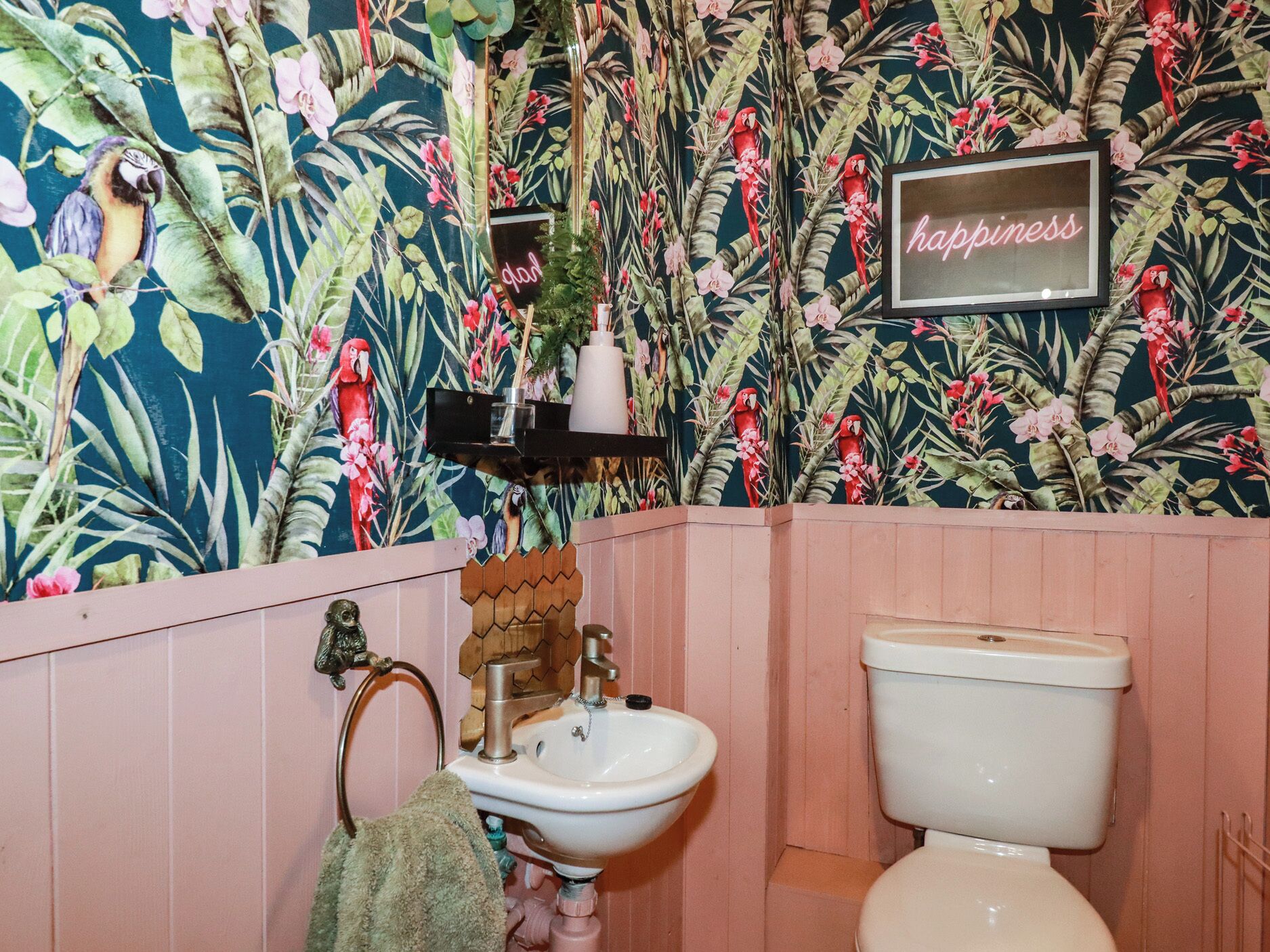 A bathroom with a floral wallpaper, a toilet, a sink, and a mirror.