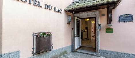 The entrance to HOTEL DU LAC with a stone-paved entrance and a flower planter.