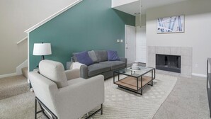 A living room with a staircase, a sofa, a coffee table, and a fireplace.