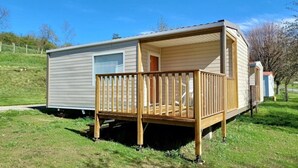 Une maison mobile dotée d’une terrasse en bois et d’un porche abrité.