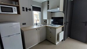 Une cuisine compacte équipée d’un réfrigérateur, d’un four à micro-ondes, d’une cuisinière et d’un évier.
