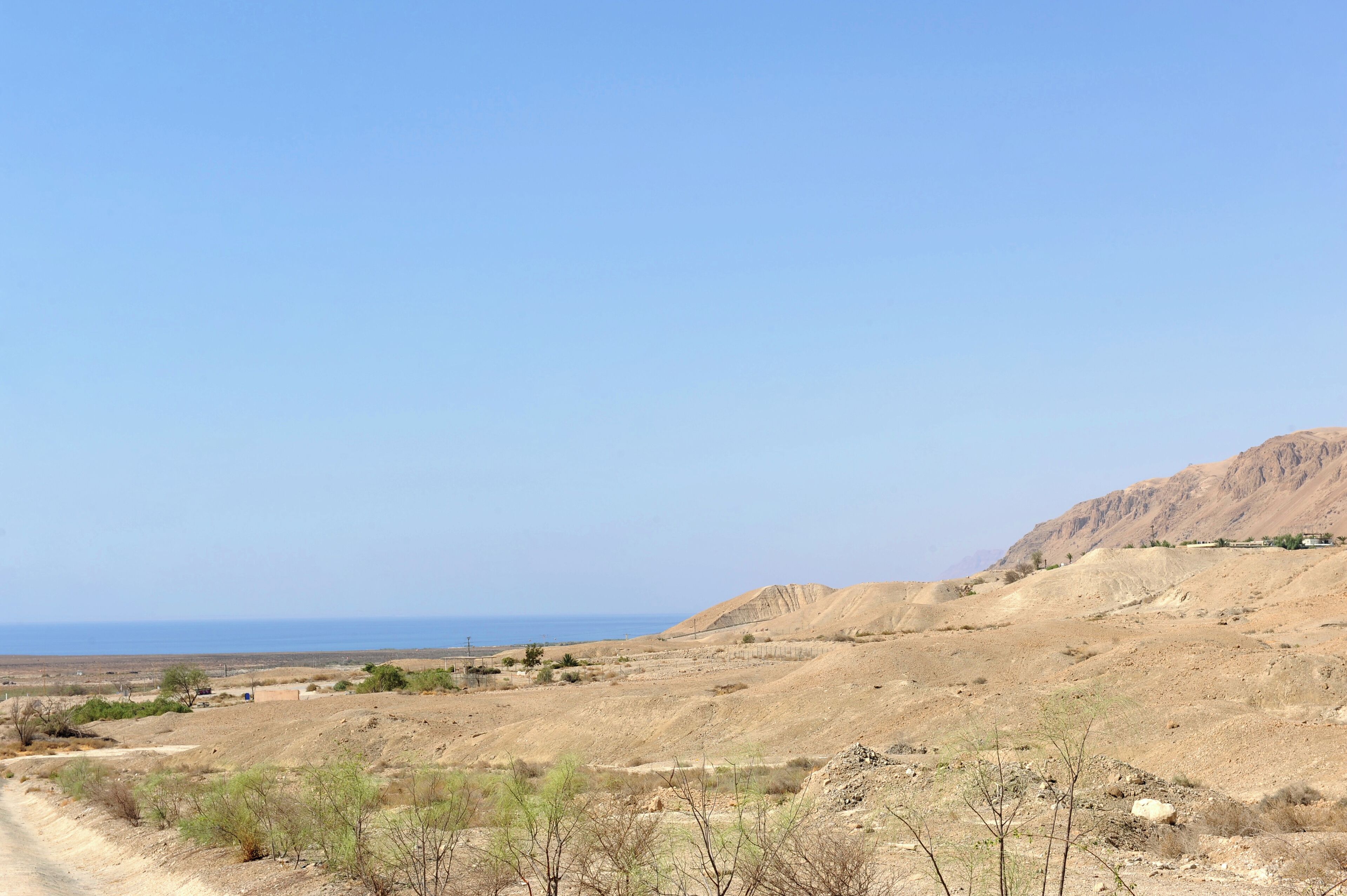 Paisaje desértico con un camino de tierra que conduce a un poblado.