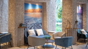 A lobby with stone walls, a large painting of a beach scene, and modern seating arrangements. - Kalya Kibbutz Hotel (Kalya)