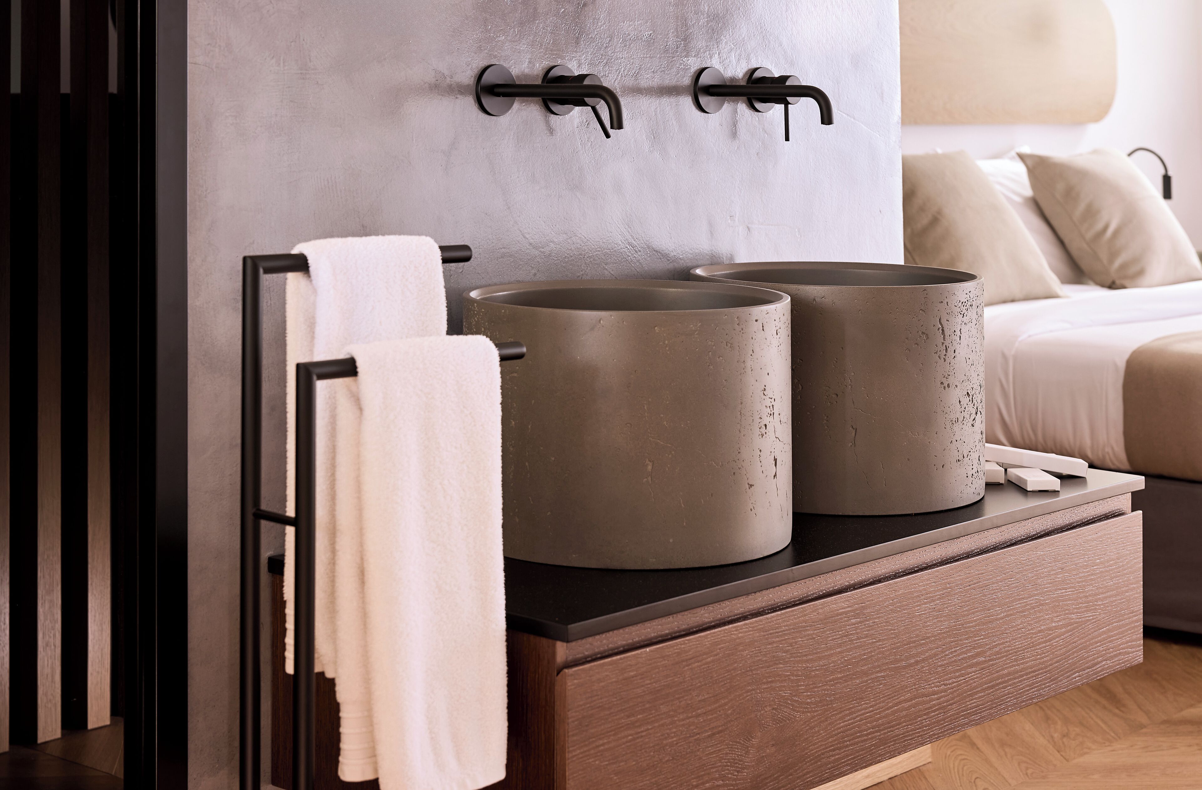 Un baño moderno con un perchero, dos recipientes cilíndricos grandes y un mueble de madera.